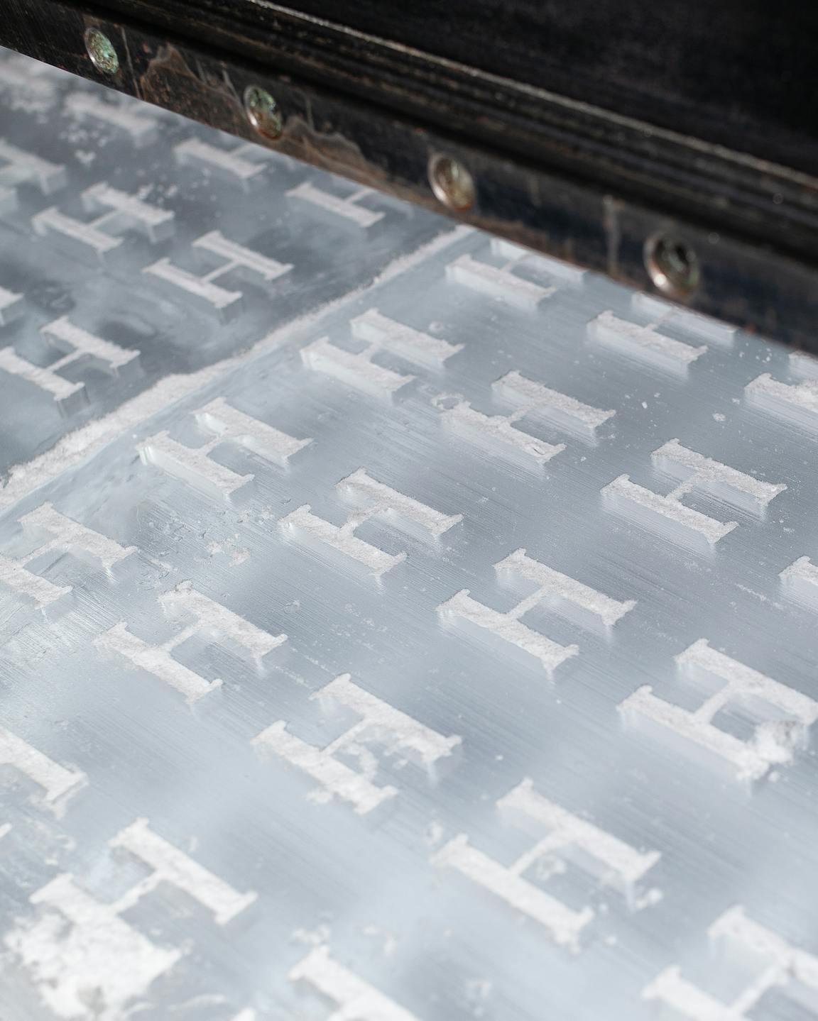 A machine engraves many "h"s into a sheet of ice.